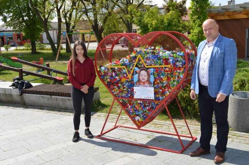 Na zdjęciu Wójt Gminy Raków - Damian Szpak wraz mieszkanką gminy Raków przy metalowym sercu na nakrętki