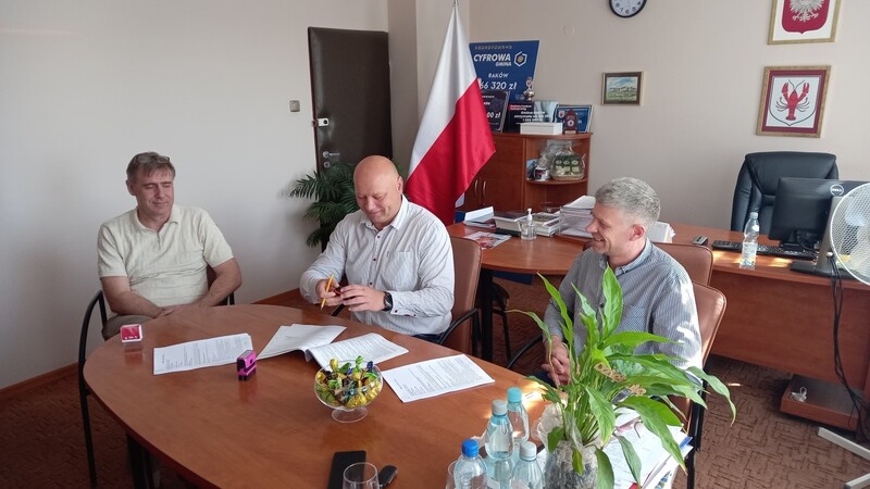 Podpisanie umowy. Na zdjęciu trzy osoby. Od lewej strony: Artur Nadolny - Skarbnik Gminy Raków, Damian Szpak - Wójt Gminy Raków oraz osoba reprezentująca firmę KORBUD. 