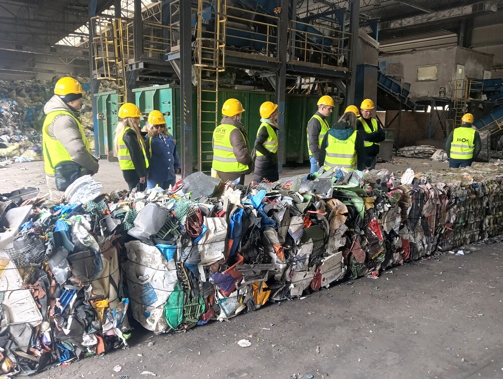 Grupa 10 ludzi w trakcie wizytacji zakładu gospodarki odpadami